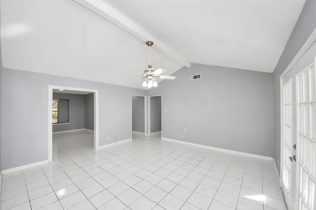 an empty room with chandelier fan and windows