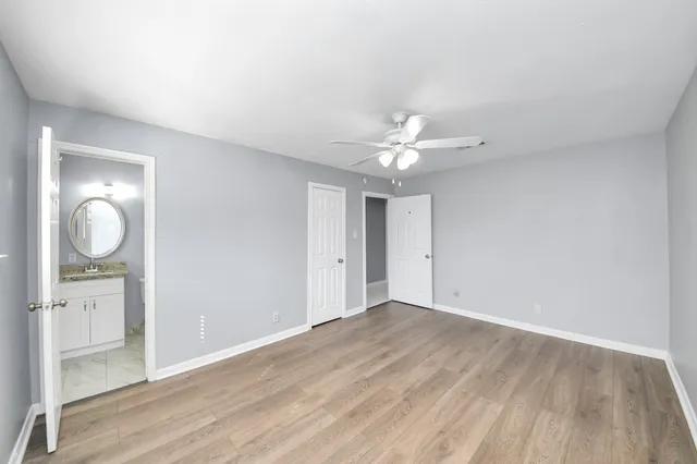 an empty room with wooden floor closet and windows