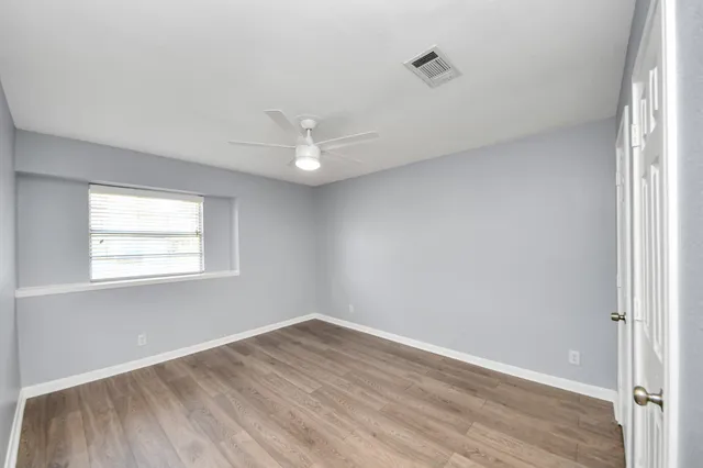 an empty room with wooden floor and window