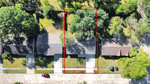 an aerial view of residential houses with outdoor space and trees