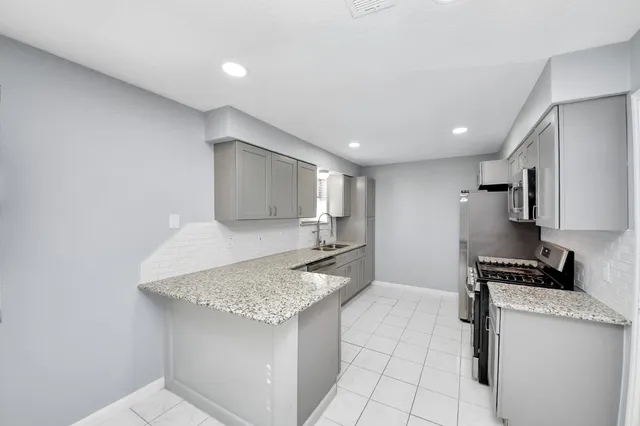 a kitchen with granite countertop a sink stove and microwave