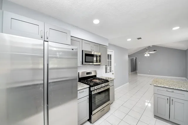 a kitchen with stainless steel appliances kitchen island granite countertop a refrigerator and a sink