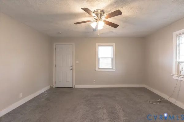 an empty room with a window and a fan