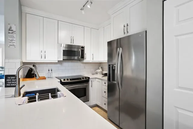 a kitchen with stainless steel appliances granite countertop a refrigerator and a stove top oven