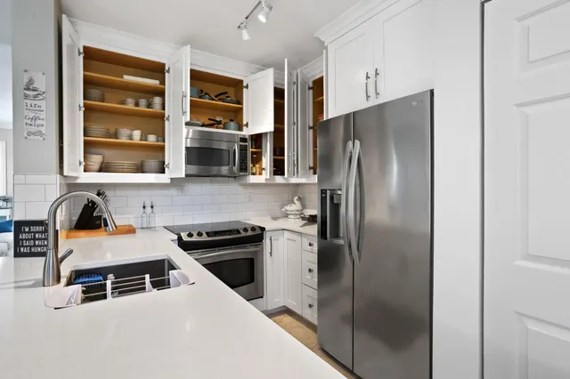 a kitchen with stainless steel appliances granite countertop a refrigerator and a stove top oven