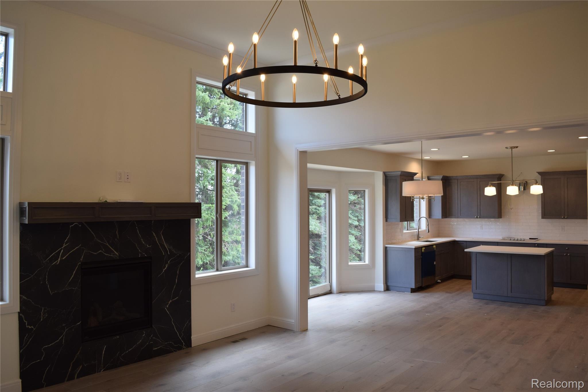 3093 Raffler Drive Rochester, MI 48307 - Photo 17 of 34 Kitchen featuring light countertops, decorative light fixtures, a center island, wood finished floors, and a high end fireplace