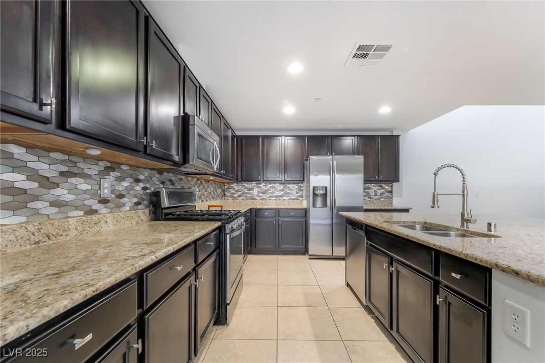 3052 Camino Rico Avenue Henderson, NV 89044 - Photo 15 of 39 Kitchen featuring backsplash, stainless steel appliances, light stone counters, light tile patterned flooring, and recessed lighting