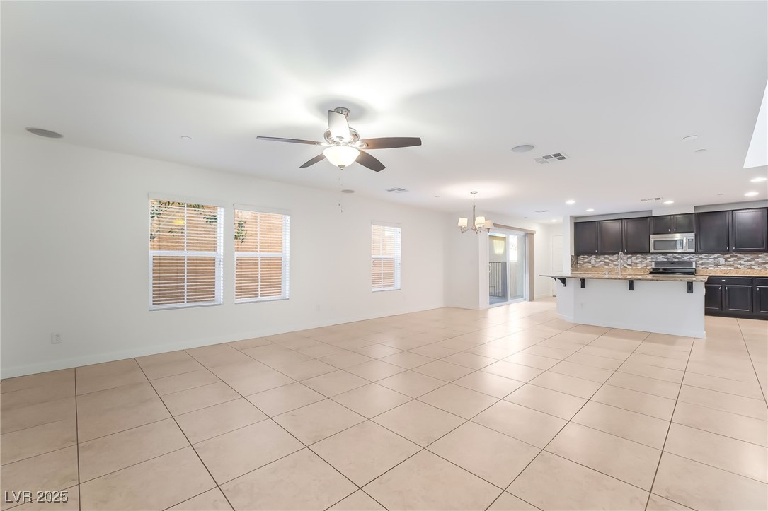 3052 Camino Rico Avenue Henderson, NV 89044 - Photo 9 of 39 Unfurnished living room featuring light tile patterned floors, a ceiling fan, a chandelier, and recessed lighting