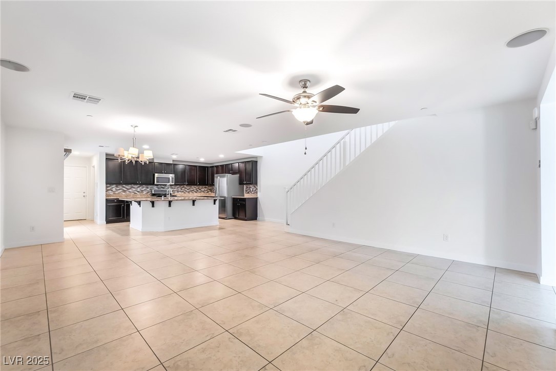 3052 Camino Rico Avenue Henderson, NV 89044 - Photo 10 of 39 Unfurnished living room with light tile patterned flooring, ceiling fan, a chandelier, and stairway
