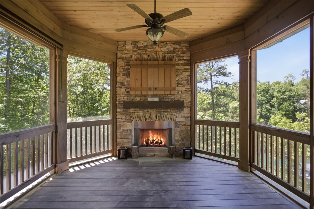 130 River Ridge Road Sunset, SC 29685 - Photo 12 of 47 This rustic screened porch offers a cozy stone fireplace, ideal for year-round enjoyment amid verdant surroundings.