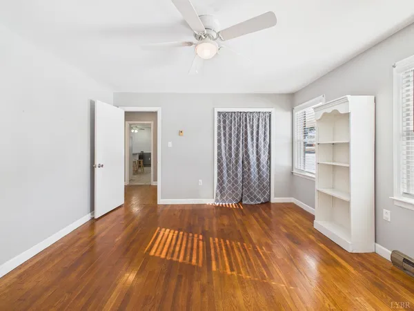 an empty room with wooden floor and fan