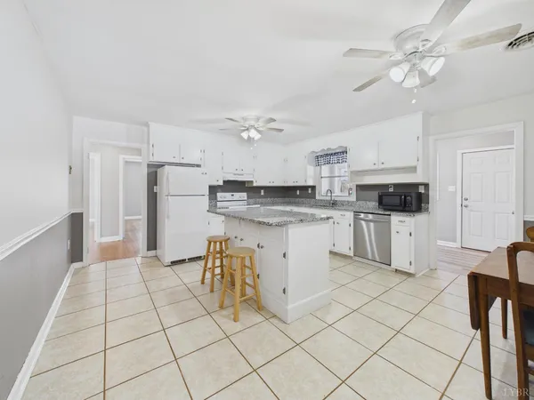 a kitchen with granite countertop a sink white cabinets and white appliances