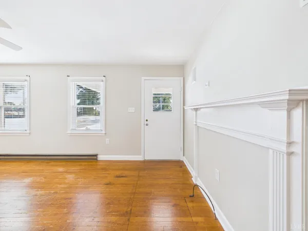 a view of an empty room with wooden floor and a window