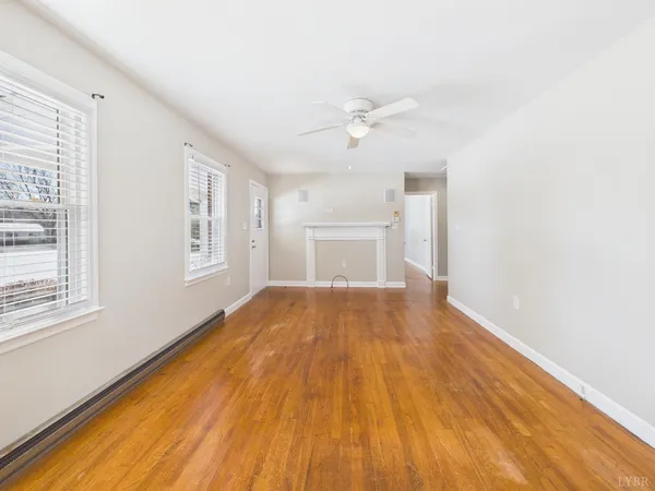 a view of empty room with wooden floor and fan