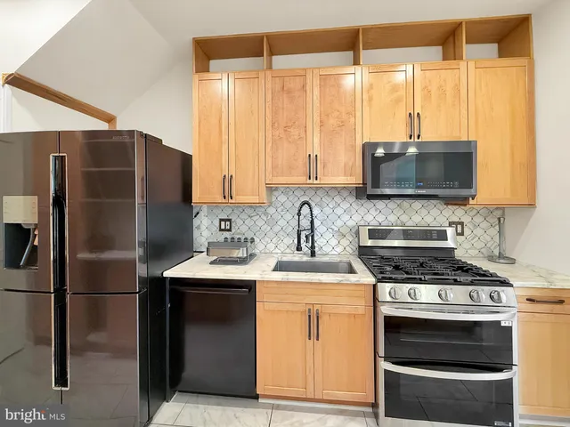 a kitchen with stainless steel appliances a stove a sink a refrigerator and a window