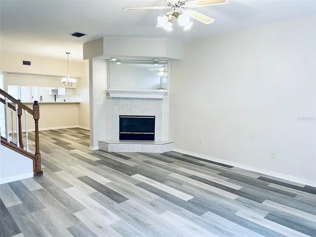 a view of an empty room with wooden floor and a fireplace