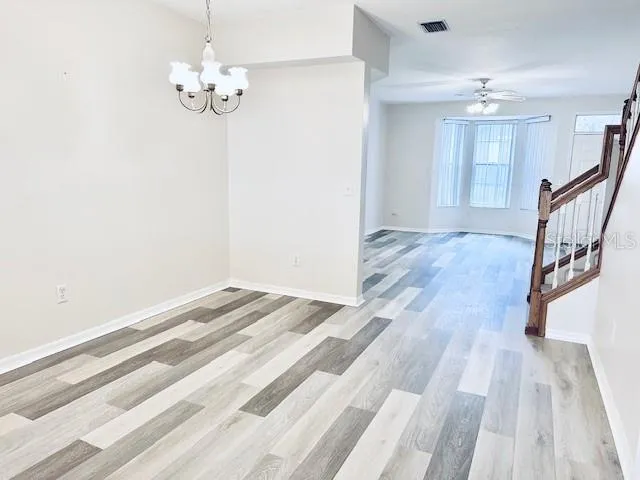 a view of an empty room with wooden floor and stairs