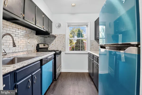 a kitchen with stainless steel appliances granite countertop a sink a stove and a refrigerator with wooden cabinets