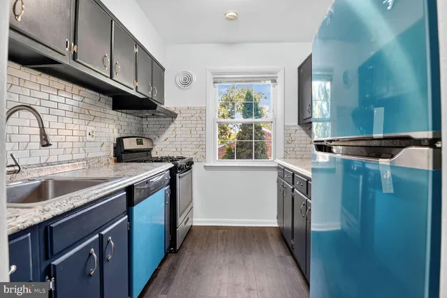 a kitchen with stainless steel appliances granite countertop a sink a stove and a refrigerator with wooden cabinets