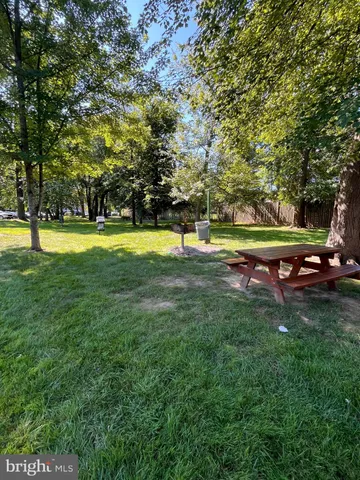a view of a swimming pool with lawn chairs and large trees