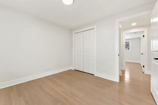 a view of an empty room with wooden floor and a bathroom