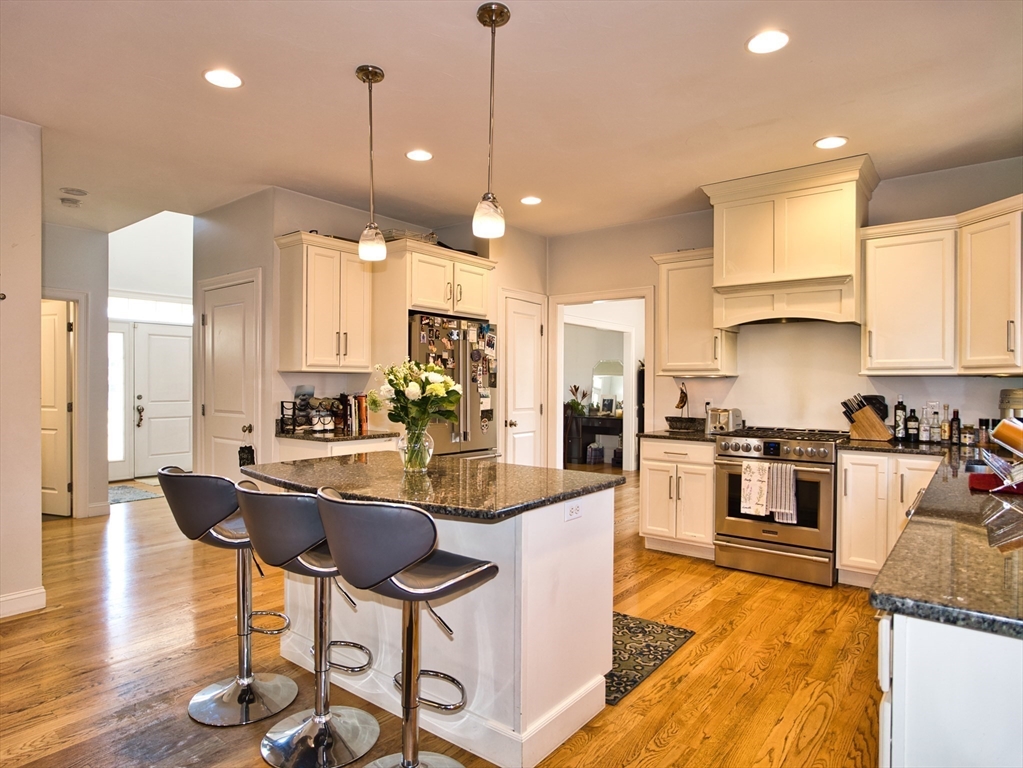 9 Brookfield Lane Bellingham, MA 02019 - Photo 10 of 40 a kitchen with stainless steel appliances kitchen island granite countertop a stove a sink a refrigerator and chairs with wooden floor