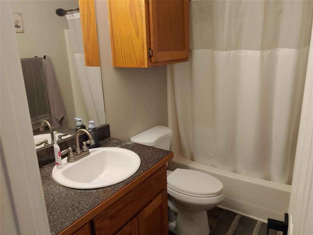 836 Airport Road Reno, TX 75462 - Photo 18 of 30 Bathroom featuring a vanity with a white oval sink, brushed nickel faucet, and a dark speckled countertop