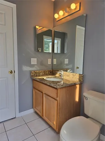 a bathroom with a granite countertop toilet sink and mirror