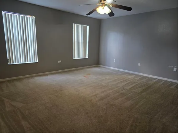 an empty room with windows and fan
