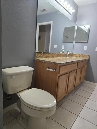a bathroom with a granite countertop toilet a sink and mirror