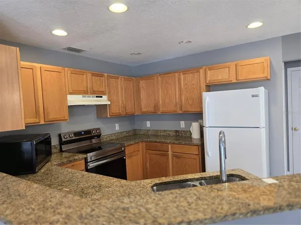 a kitchen with stainless steel appliances granite countertop a refrigerator sink and cabinets