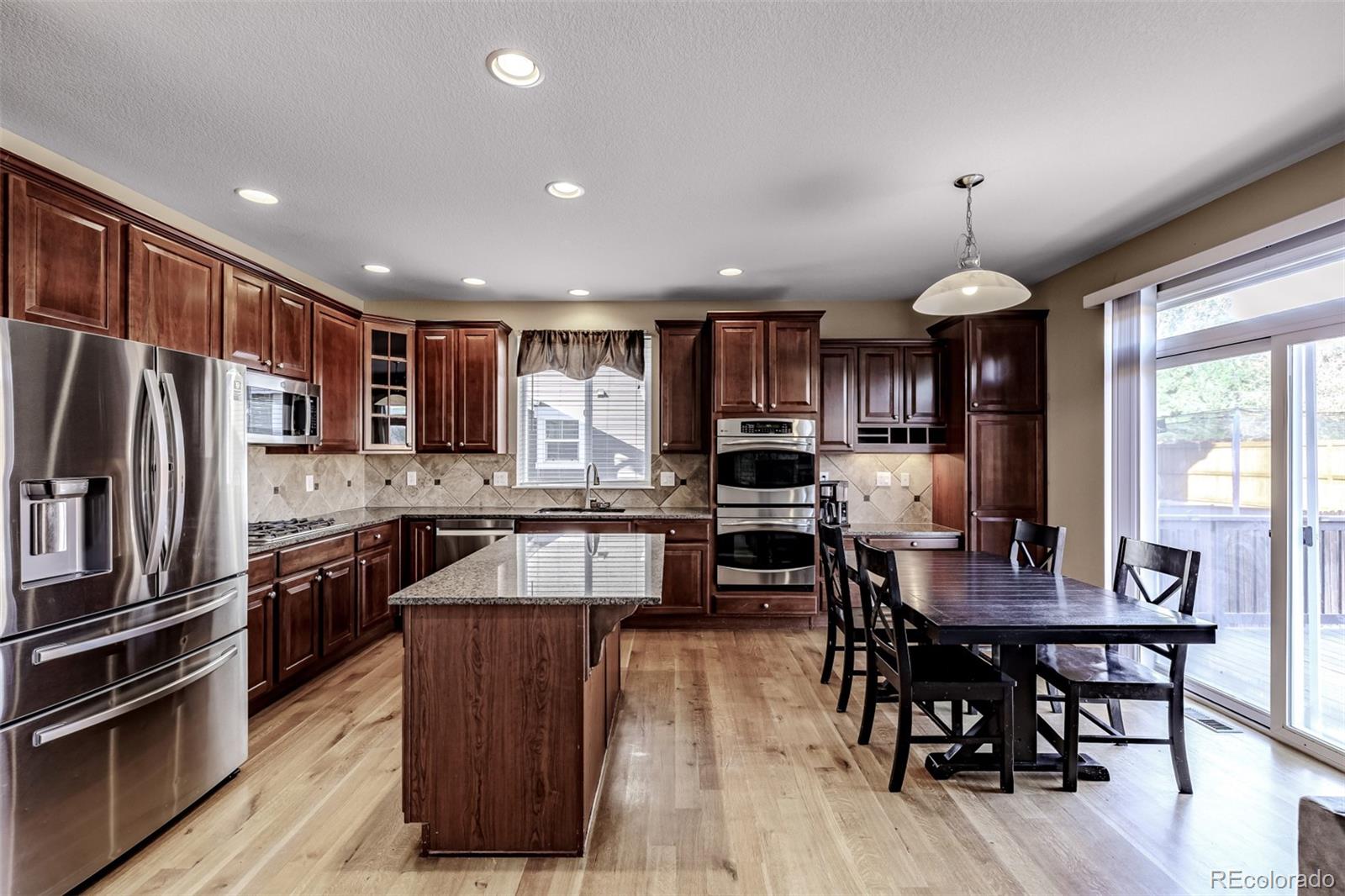 139 Muscovey Lane Johnstown, CO 80534 - Photo 13 of 49 a kitchen with stainless steel appliances granite countertop a stove top oven a sink dishwasher a dining table and chairs with wooden floor