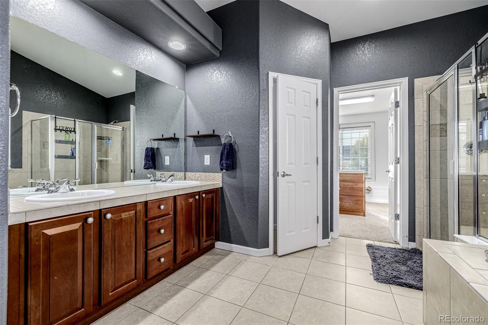 139 Muscovey Lane Johnstown, CO 80534 - Photo 19 of 49 a bathroom with a sink a large mirror and a shower