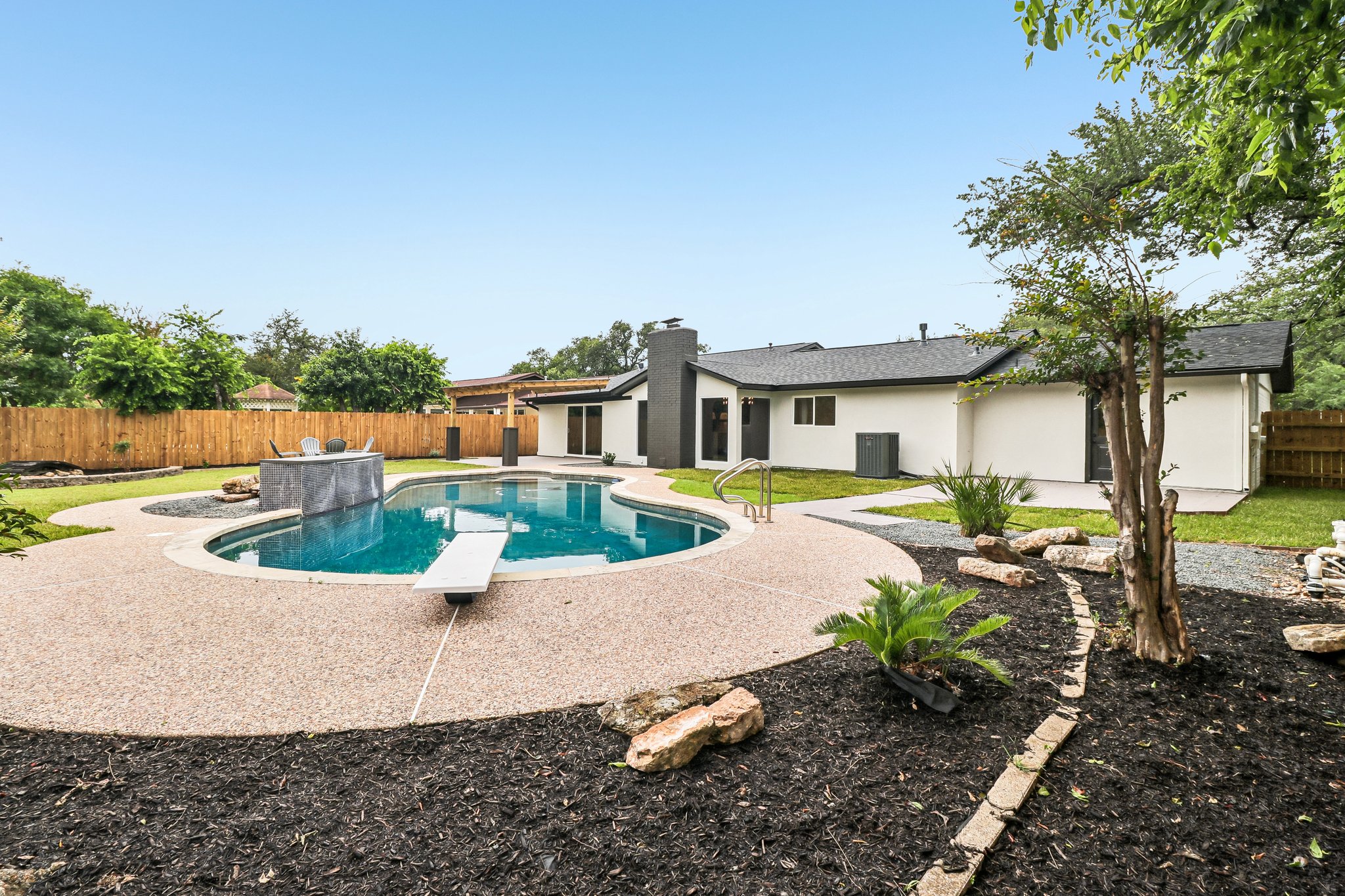 11809 Charing Cross Road Austin, TX 78759 - Photo 2 of 34 A private backyard oasis features a freeform pool with diving board and a sleek, built-in outdoor bar.