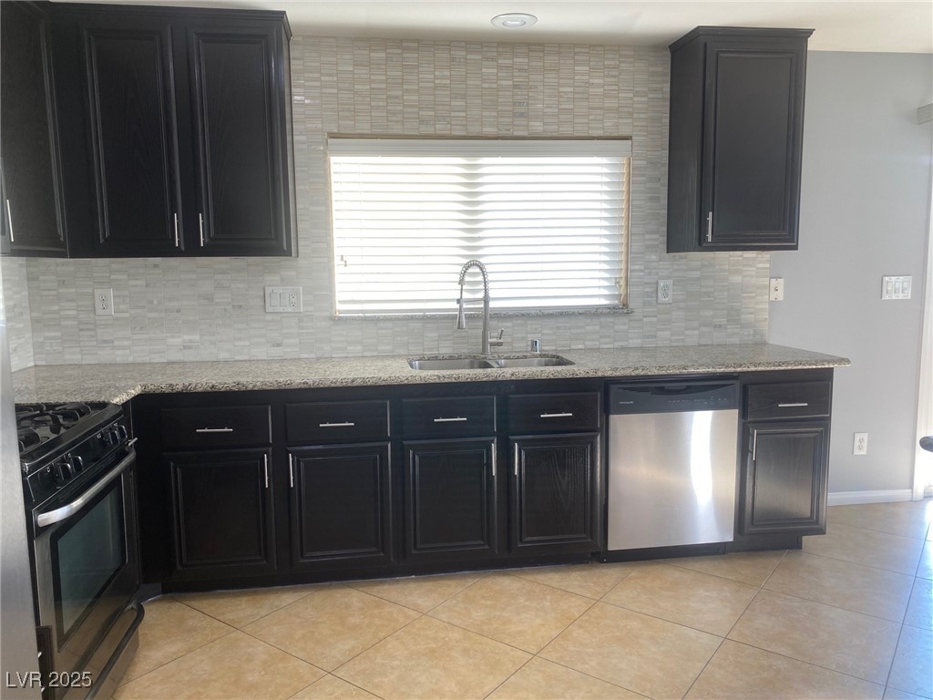 9541 Vast Valley Avenue Las Vegas, NV 89148 - Photo 11 of 32 Kitchen with dark cabinets, appliances with stainless steel finishes, and light stone counters