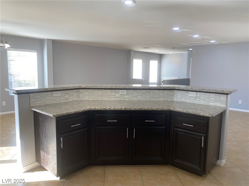 9541 Vast Valley Avenue Las Vegas, NV 89148 - Photo 13 of 32 Kitchen with dark cabinetry, light tile patterned flooring, light stone countertops, a kitchen island, and recessed lighting