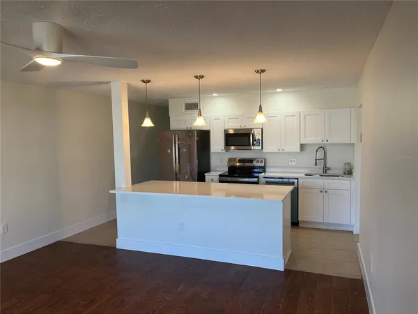 a large kitchen with stainless steel appliances a refrigerator a stove a oven a sink with a dining table and chairs