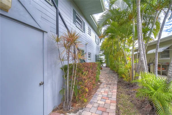a pathway of a house with a yard and potted plants