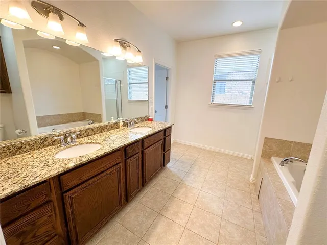 a bathroom with a granite countertop sink a mirror and a bathtub