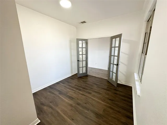 an empty room with wooden floor and window