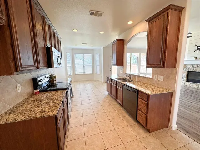 a large kitchen with stainless steel appliances granite countertop a sink and a stove