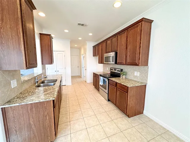 a large kitchen with stainless steel appliances granite countertop a stove a sink dishwasher and a refrigerator