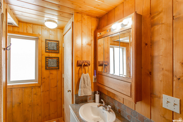 1644 West Tollgate Cyn Road, Unit 79AM Coalville, UT 84017 - Photo 21 of 31 Wood-paneled walls and ceiling, built-in medicine cabinet with integrated lighting, window for natural light, and a vanity with an integrated sink