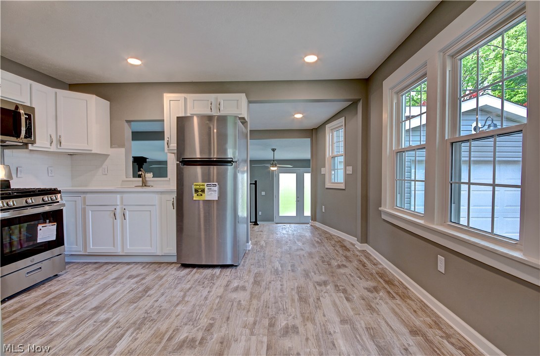 14507 Glencliffe Road Cleveland, OH 44111 - Photo 10 of 31 Kitchen featuring ceiling fan, tasteful backsplash, stainless steel appliances, light wood-type flooring, and white cabinets