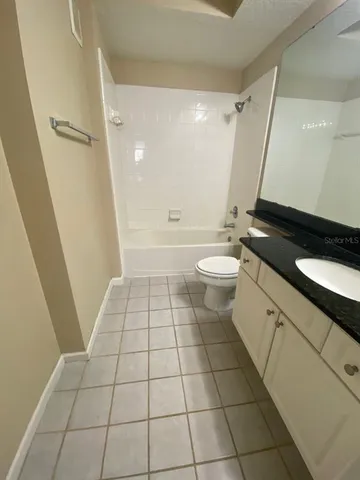 a bathroom with a granite countertop sink toilet a mirror and shower