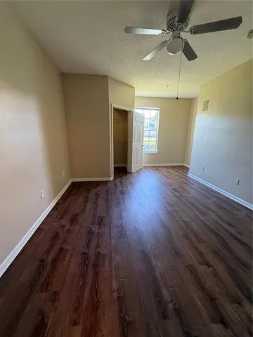 an empty room with wooden floor closet fan and windows