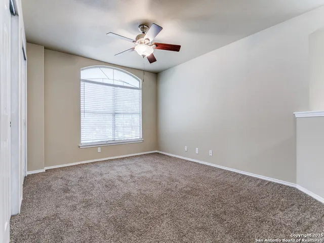 an empty room with windows and chandelier fan