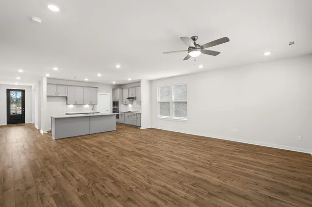 a view of an empty room with wooden floor and stairs