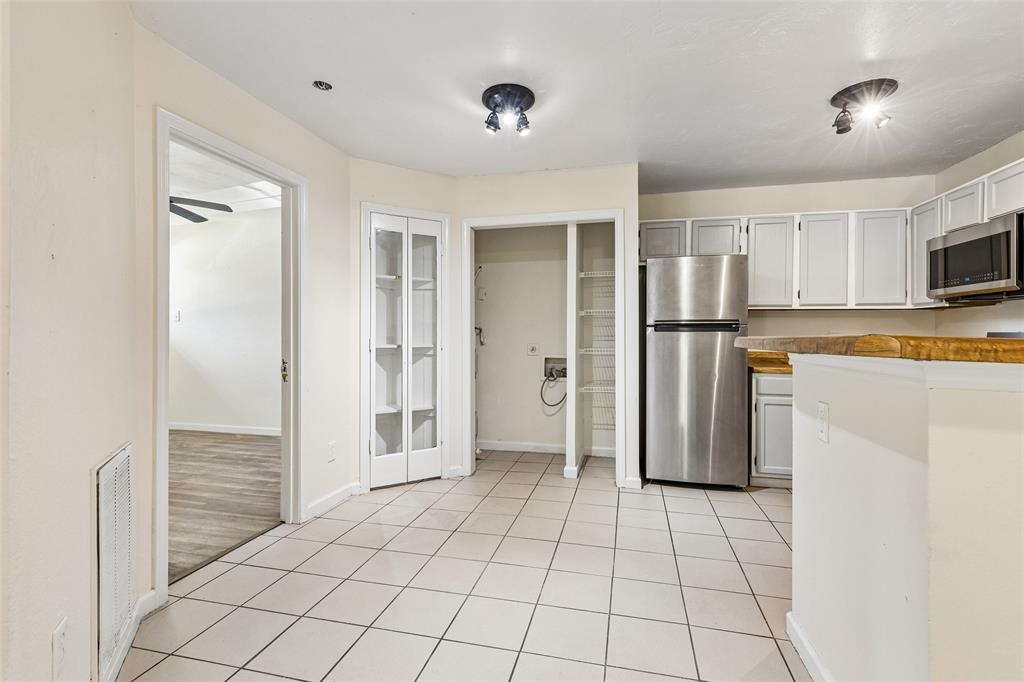 6108 Abrams Road, Unit 610 Dallas, TX 75231 - Photo 13 of 21 Kitchen area featuring light-toned tile flooring, light-toned cabinetry, and stainless steel appliances
