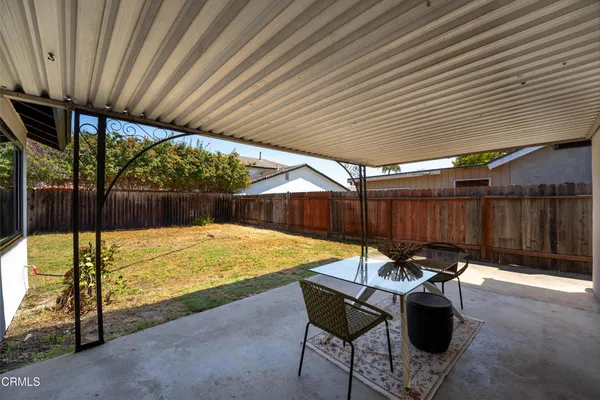 a view of a backyard with table and chairs under an umbrella with a small yard